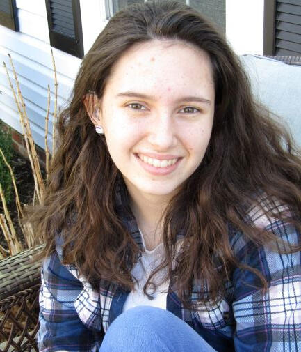 Julia Russel stares at the camera. She has a blue flannel shirt and should length hair.